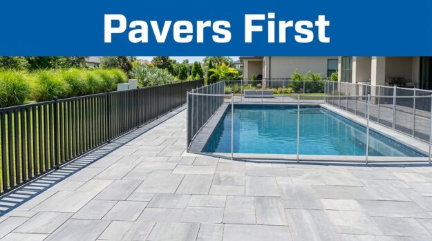 New pool deck pavers in the foreground with a safety fence and temporary mesh barrier.