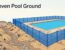 Blue mesh fencing follows uneven ground beside a turquoise pool.