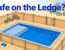 A fenced pool has a shallow ledge, closed gate, and water shoes outside.