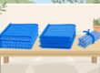 Two folded blue mesh pool fence sections and a bundled set of posts on a wooden bench.